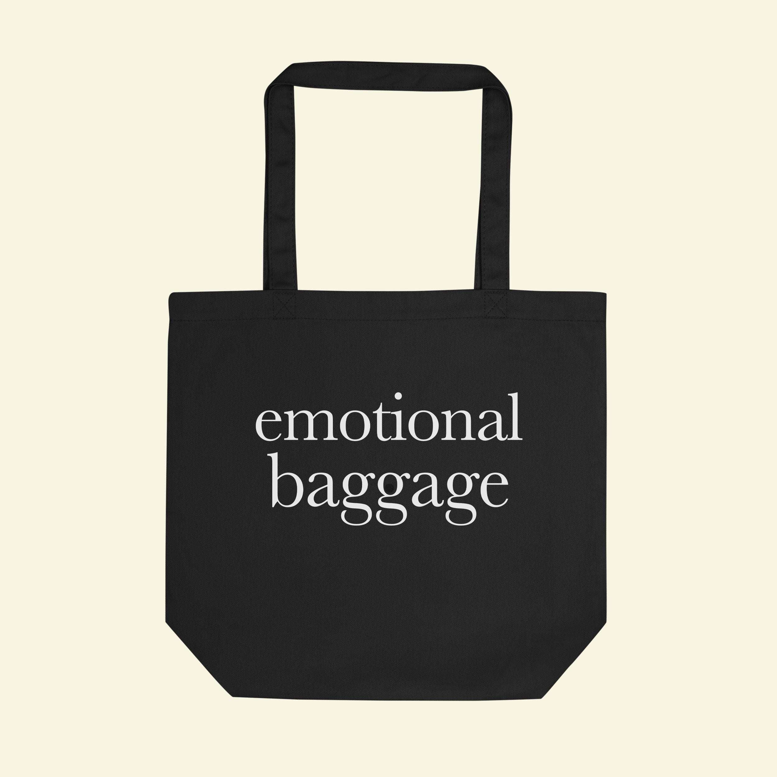 Black tote bag with short handles, featuring “emotional baggage” printed on the front.
