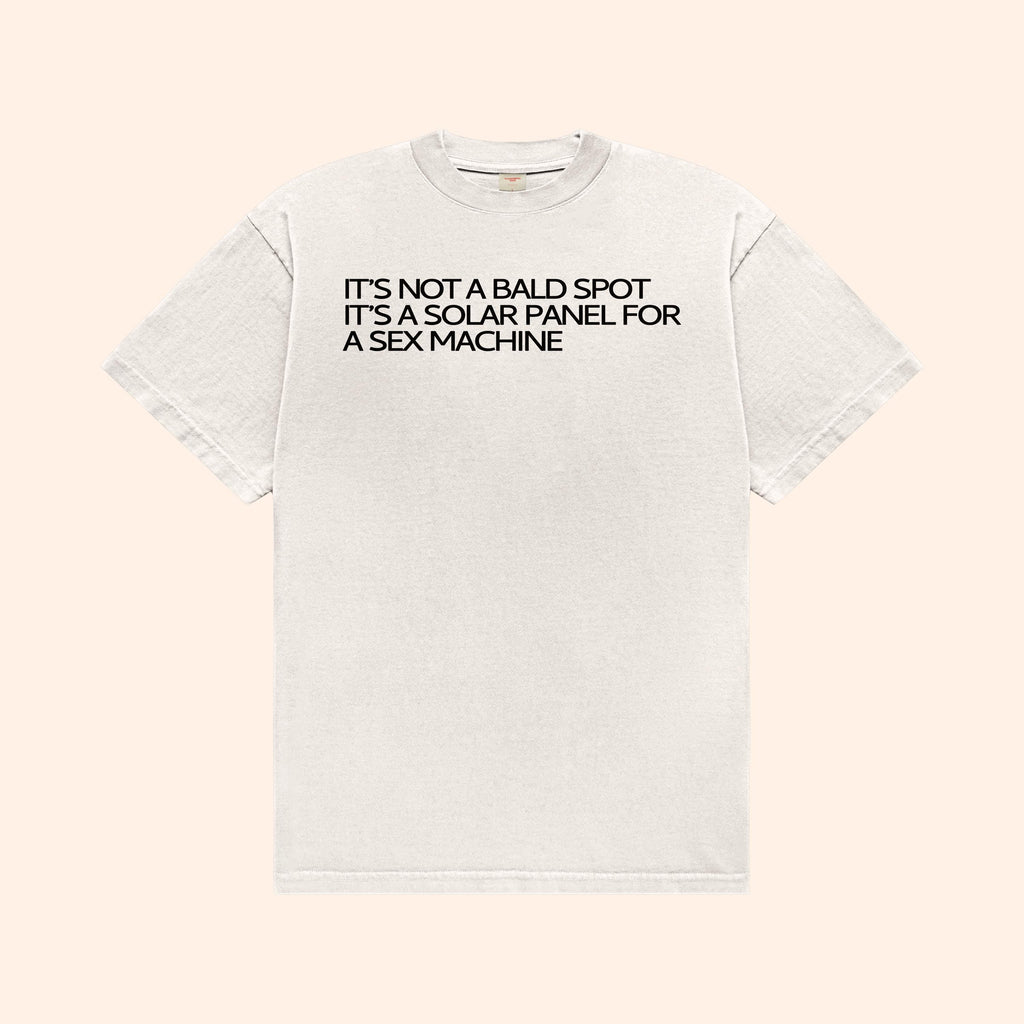 Light gray/white T-shirt with front slogan text: "IT’S NOT A BALD SPOT"