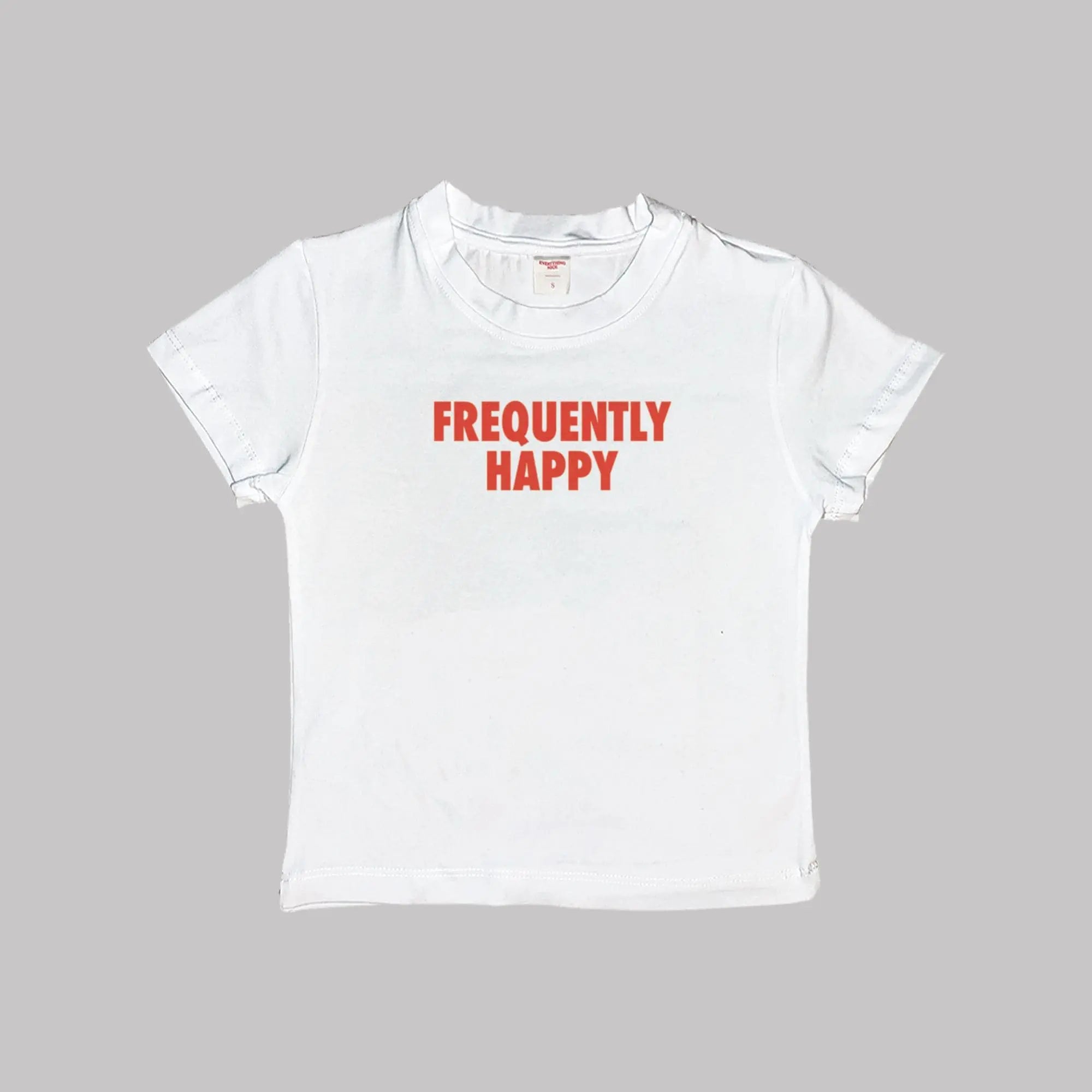 White crop baby tee with crew neck and red “FREQUENTLY HAPPY” graphic