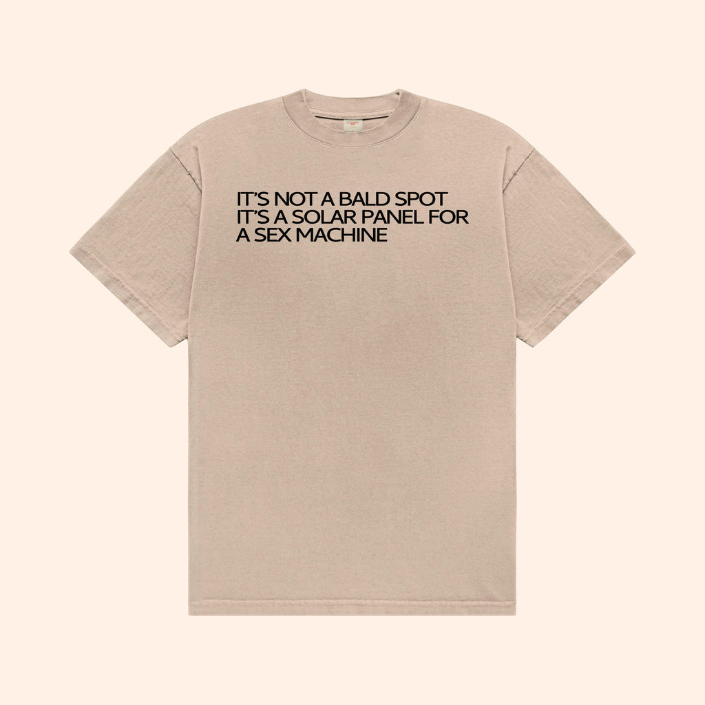 Beige T-shirt with front text graphic: "IT’S NOT A BALD SPOT"