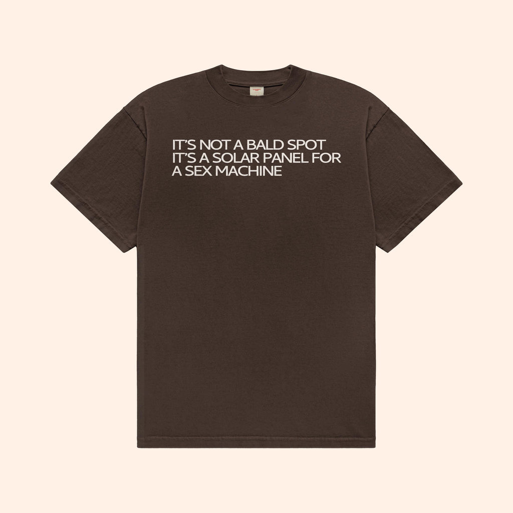 Dark brown T-shirt with front text graphic: "IT’S NOT A BALD SPOT"