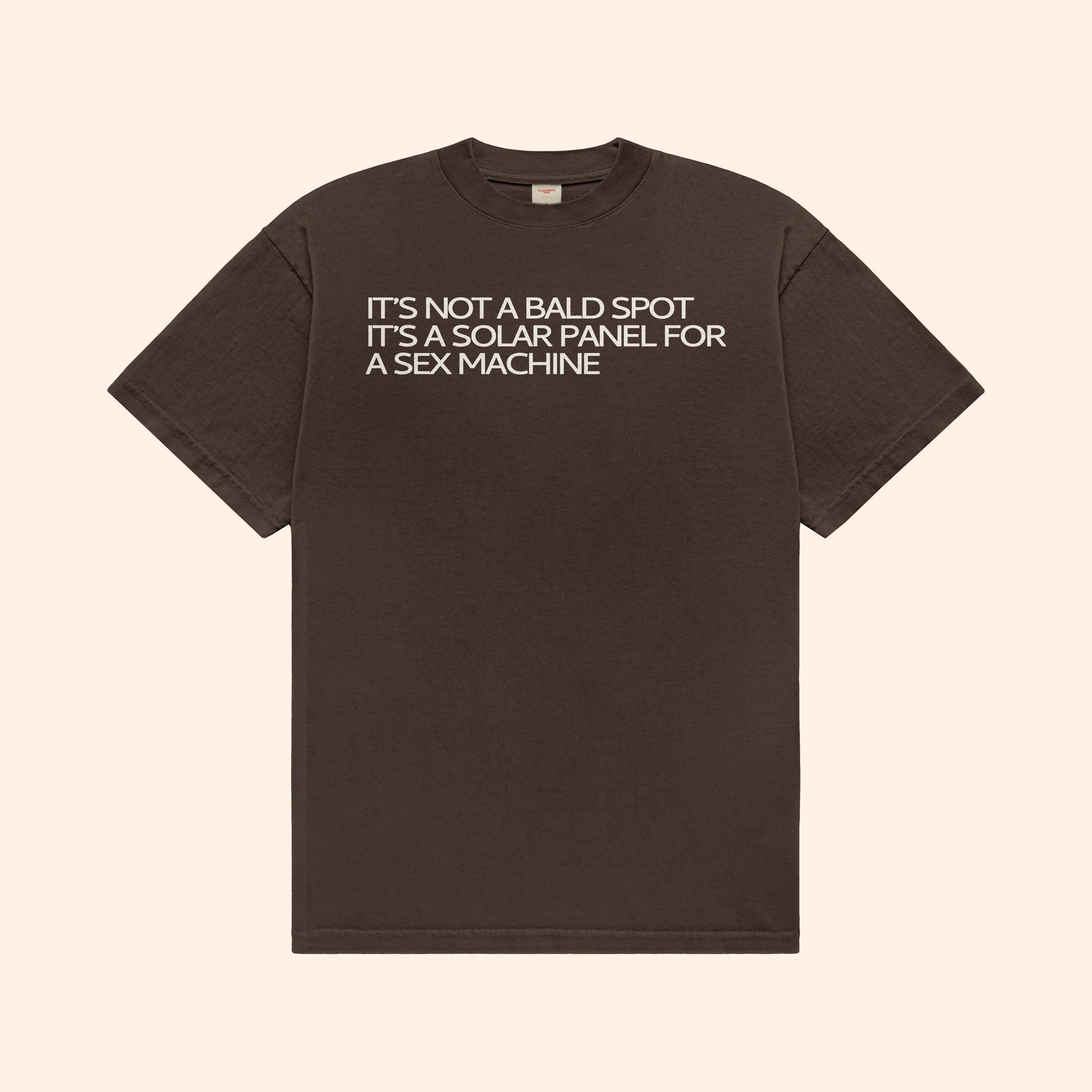 Dark brown T-shirt with front text graphic: "IT’S NOT A BALD SPOT"