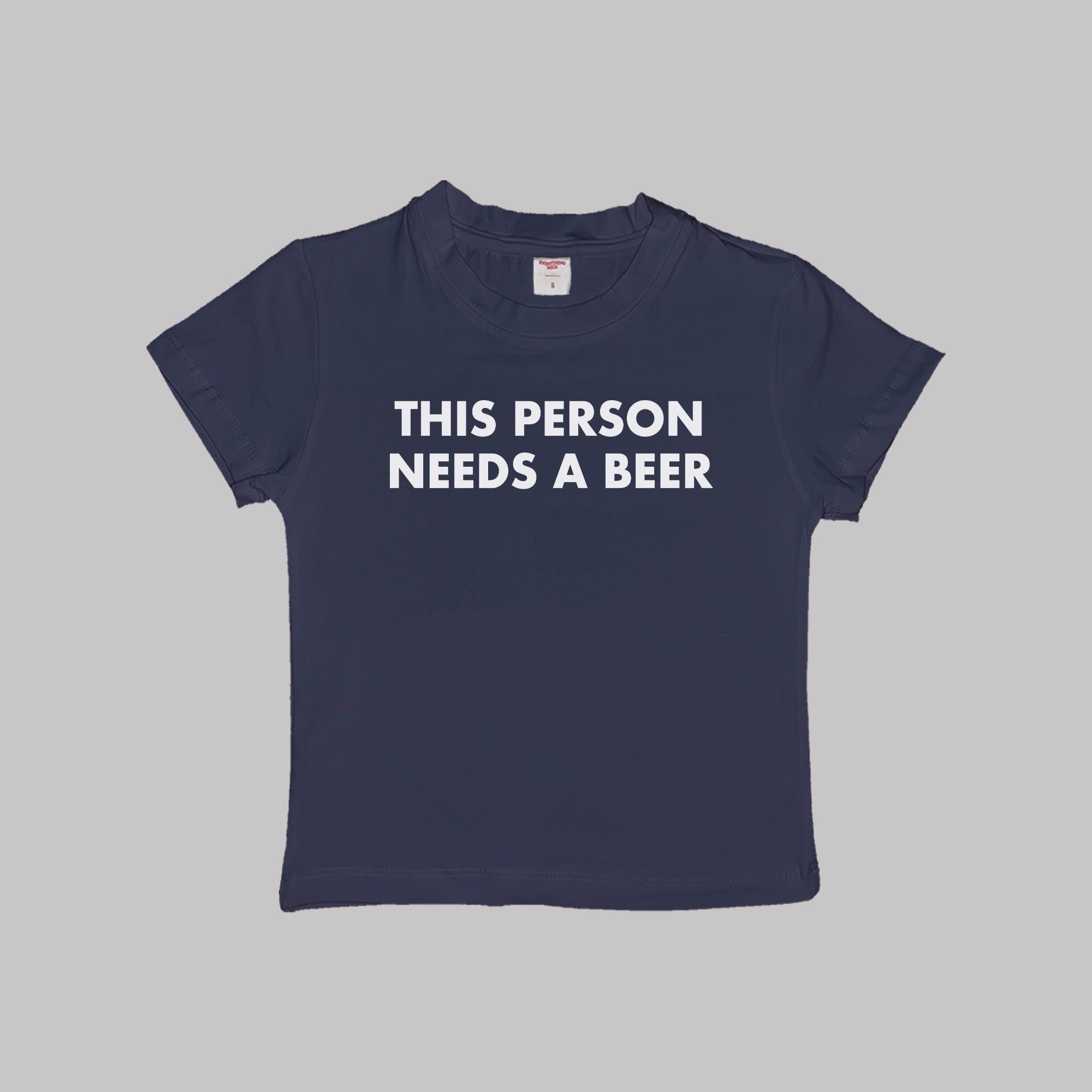 Navy cropped baby tee with “THIS PERSON NEEDS A BEER” text print