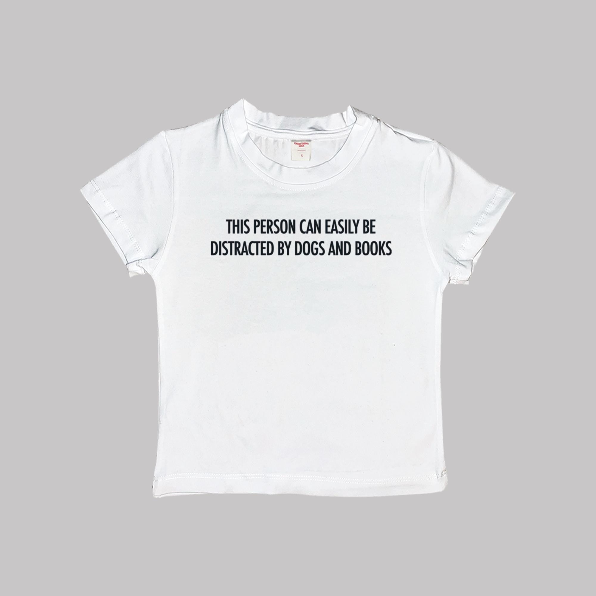 White baby T-shirt with “Dogs and books” slogan on the front
