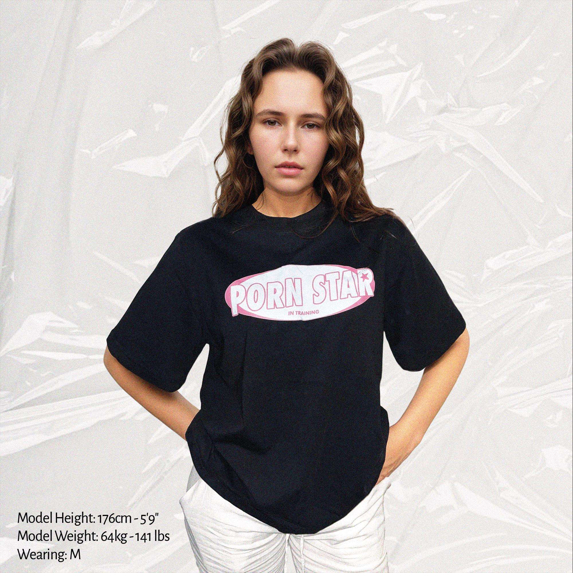 Black unisex T-shirt with centered pink 'Porn Star' oval logo on chest
