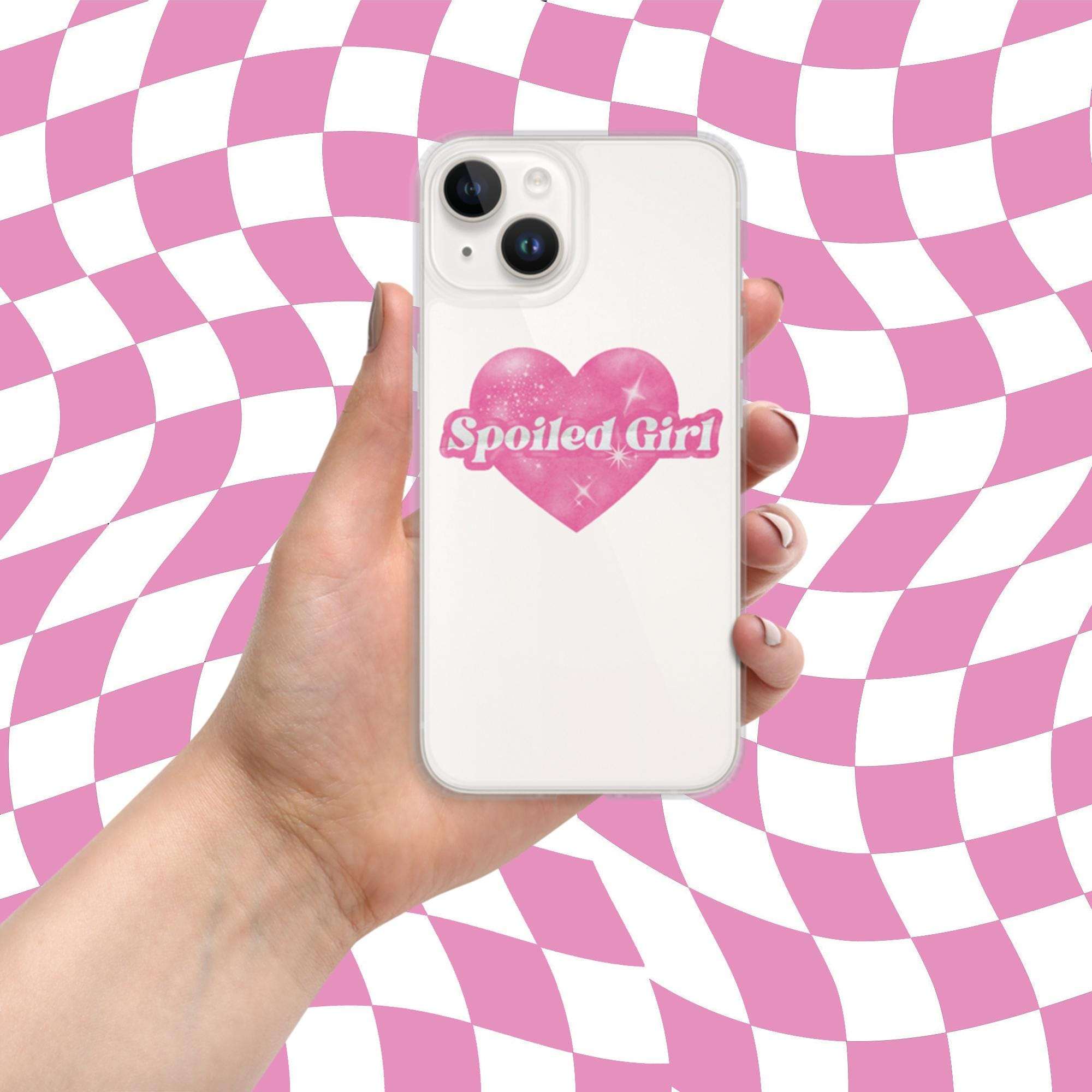 White iPhone case with pink heart 'Spoiled Girl' text, held in hand; camera cutouts