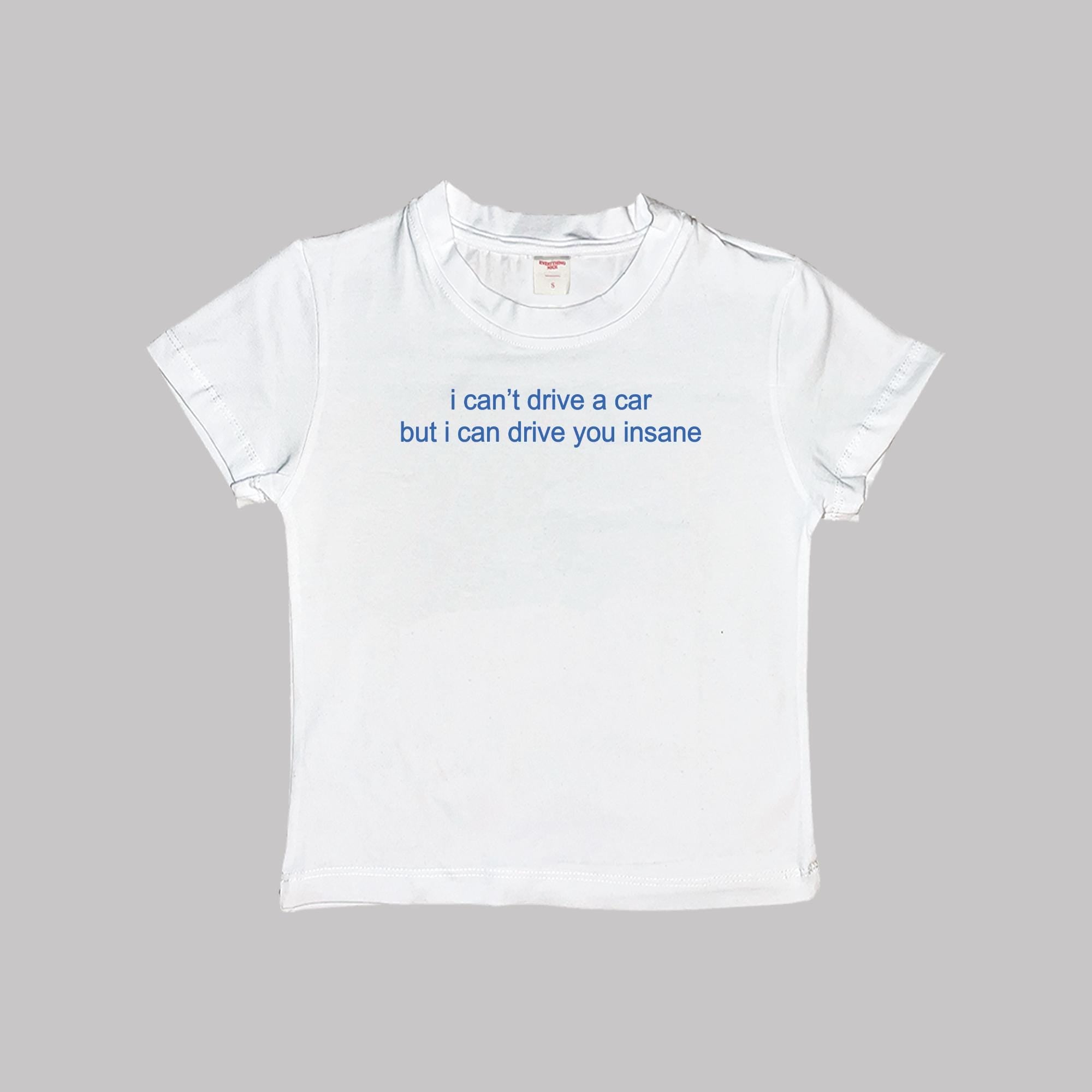 White short-sleeve crop tee with “i can’t drive a car but i can drive you insane” print