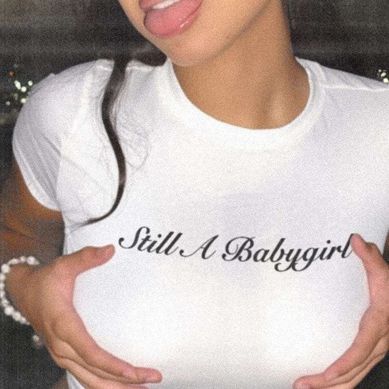 White baby tee crop top with black 'Still A Babygirl' script print