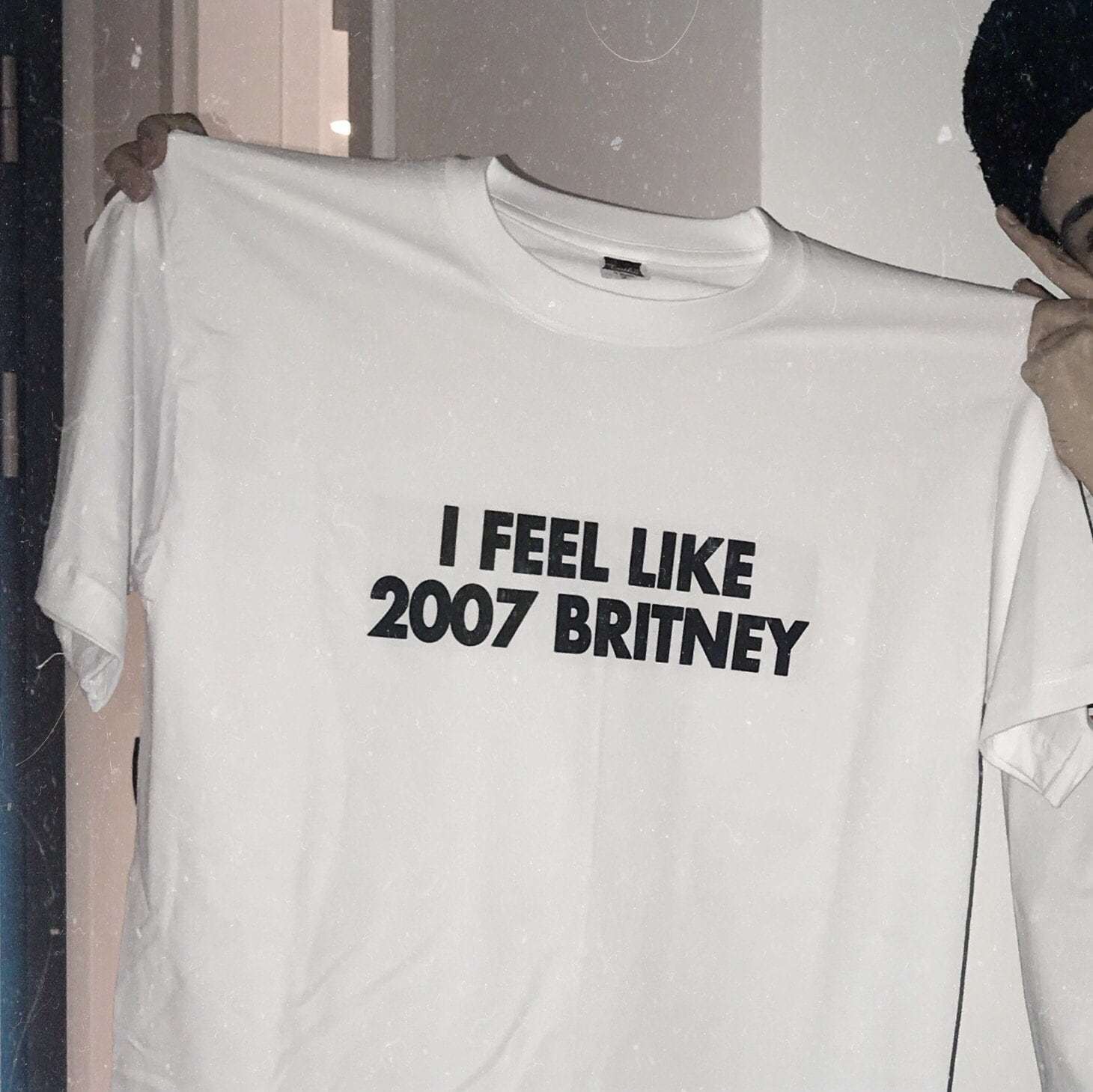 White graphic T-shirt with bold text “I FEEL LIKE 2007 BRITNEY” on front