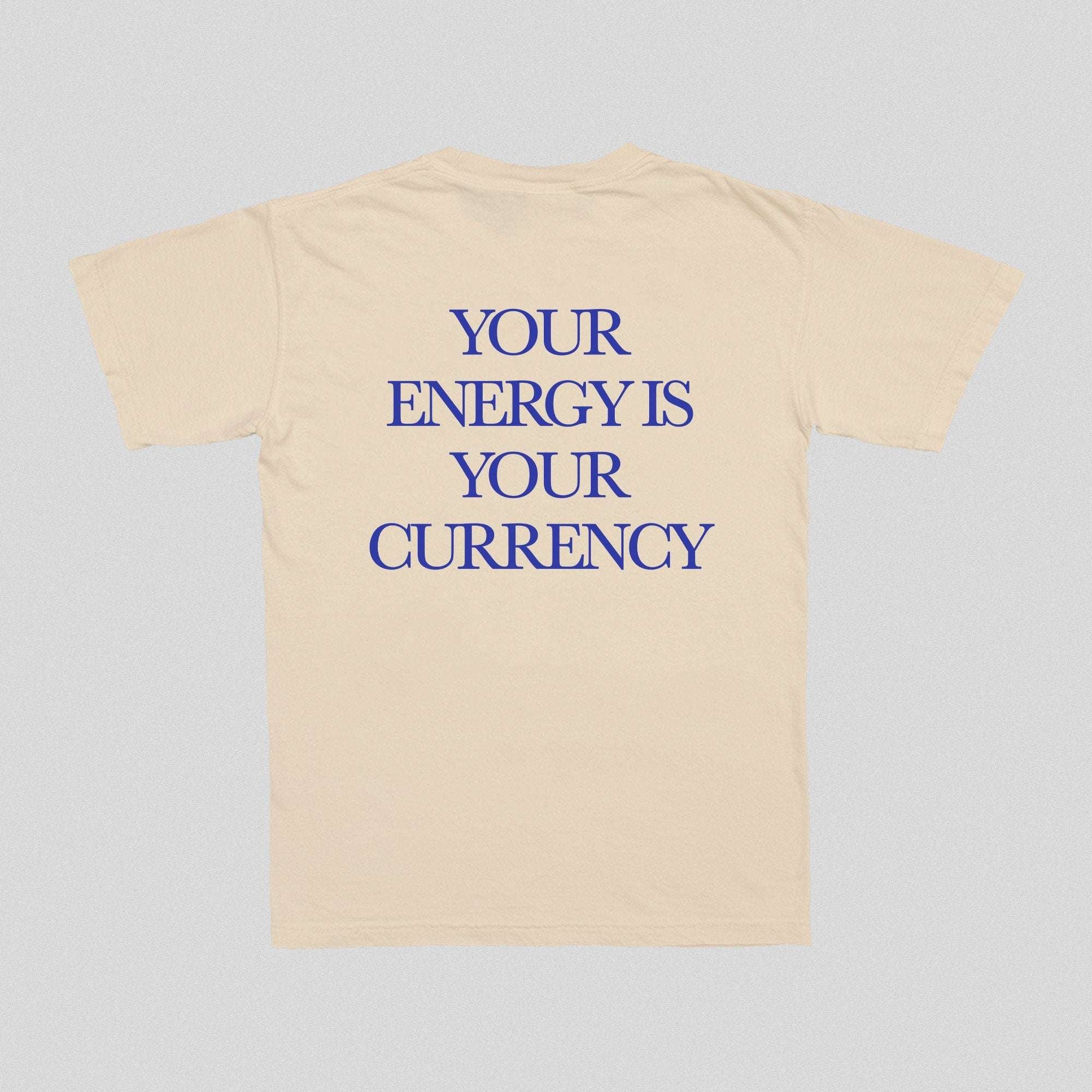 Natural/beige T-shirt with blue text “YOUR ENERGY IS YOUR CURRENCY”.