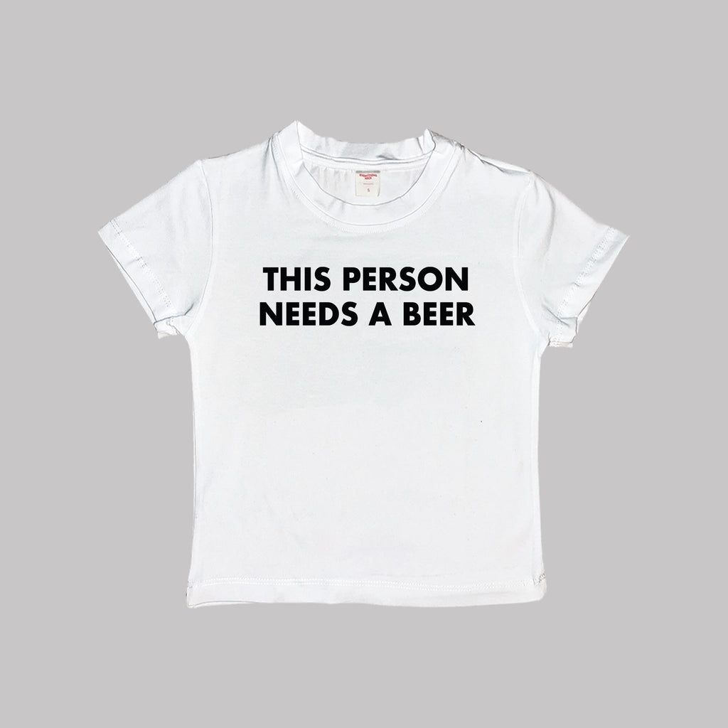 White cropped T-shirt, crew neck, “THIS PERSON NEEDS A BEER” front graphic