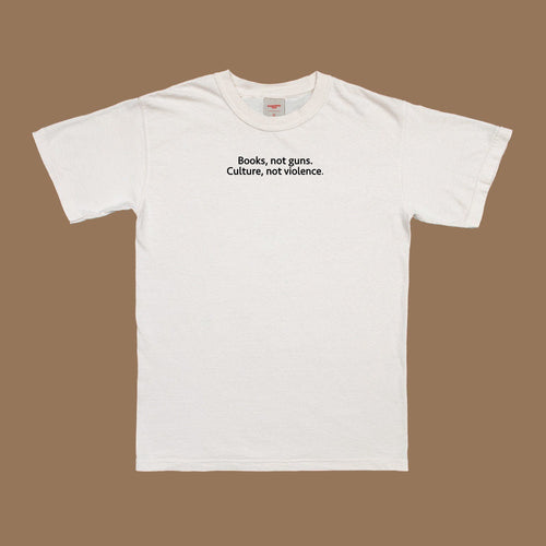 Front view white T-shirt with “Books, not guns. Culture, not violence.” text
