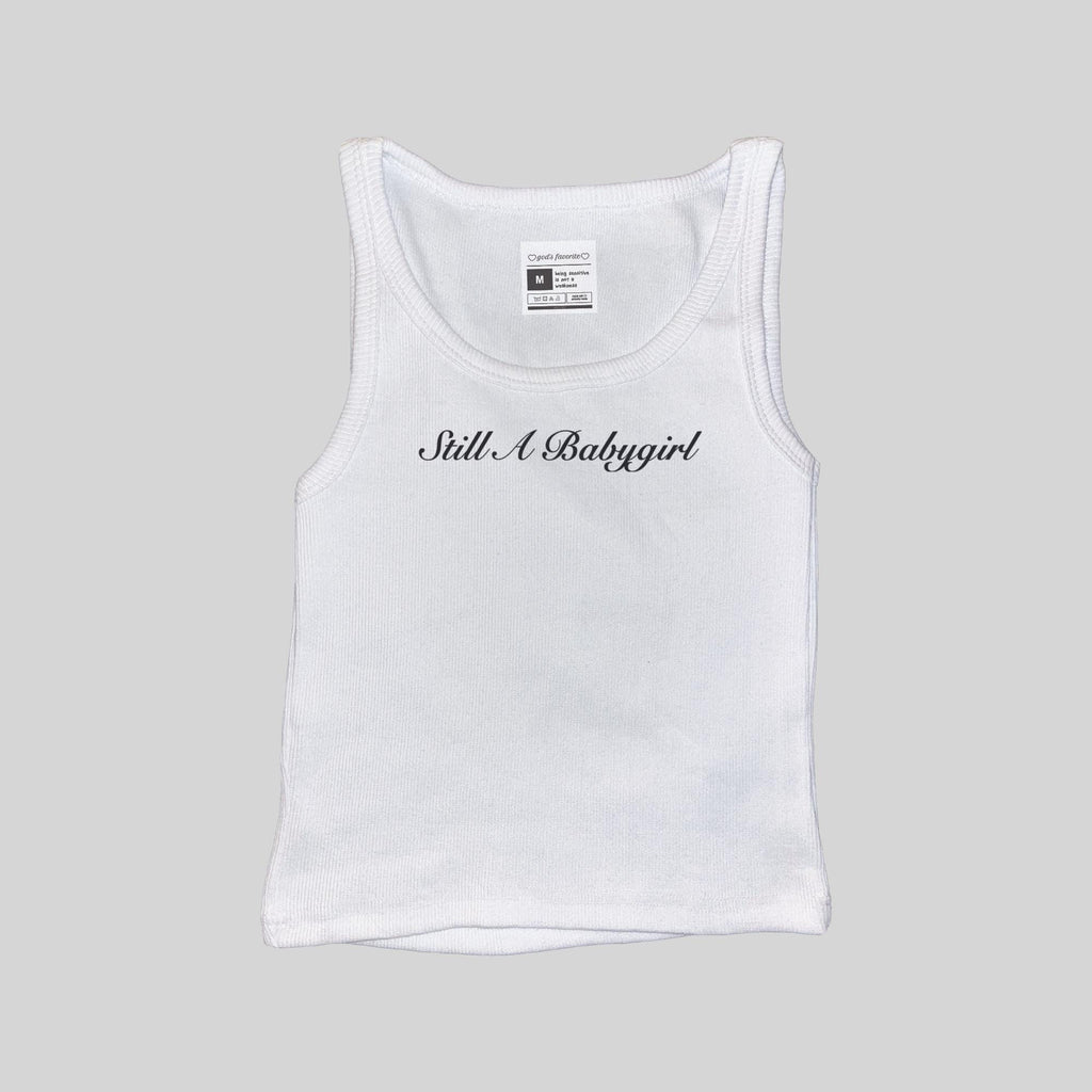 White ribbed sleeveless tank top with front 'Still A Babygirl' script, size tag