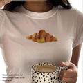 White baby tee crop top with watercolor croissant graphic on front